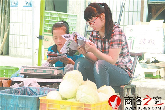 商州區(qū)楊斜鎮(zhèn)集市上，南思佳和妹妹在幫父母賣菜，閑暇之余，她們會(huì)拿起課外讀物翻一翻。在這個(gè)假期里，她們呆的最多的地方就是這個(gè)菜攤。